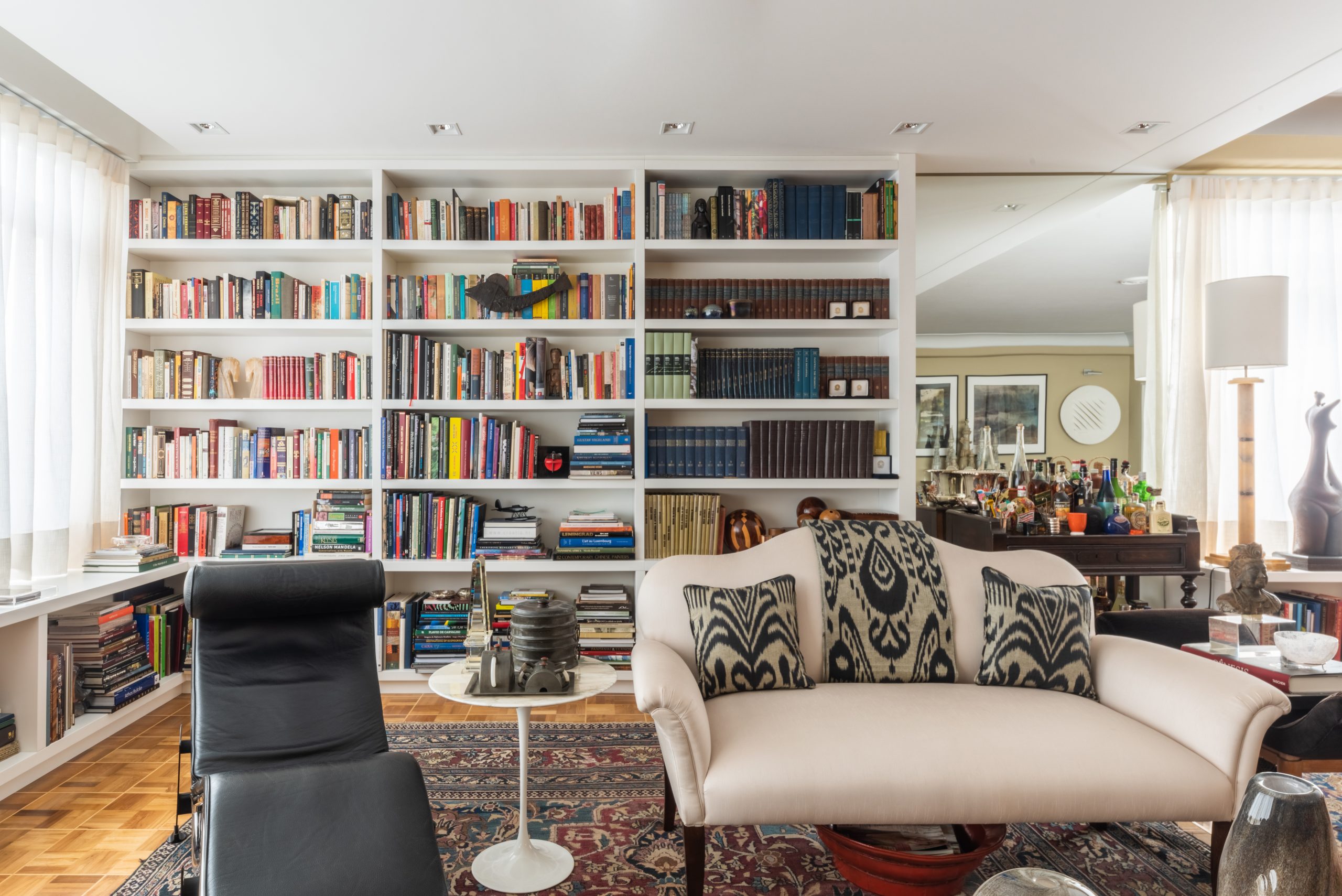 Na sala de estar deste apartamento, o arquiteto Bruno Moraes optou pelo uso de pinos invisíveis para criar o efeito de prateleiras e nicho flutuantes, proporcionando um visual moderno e elegante ao espaço | Projeto do BMA Studio | Foto: Guilherme Pucci
